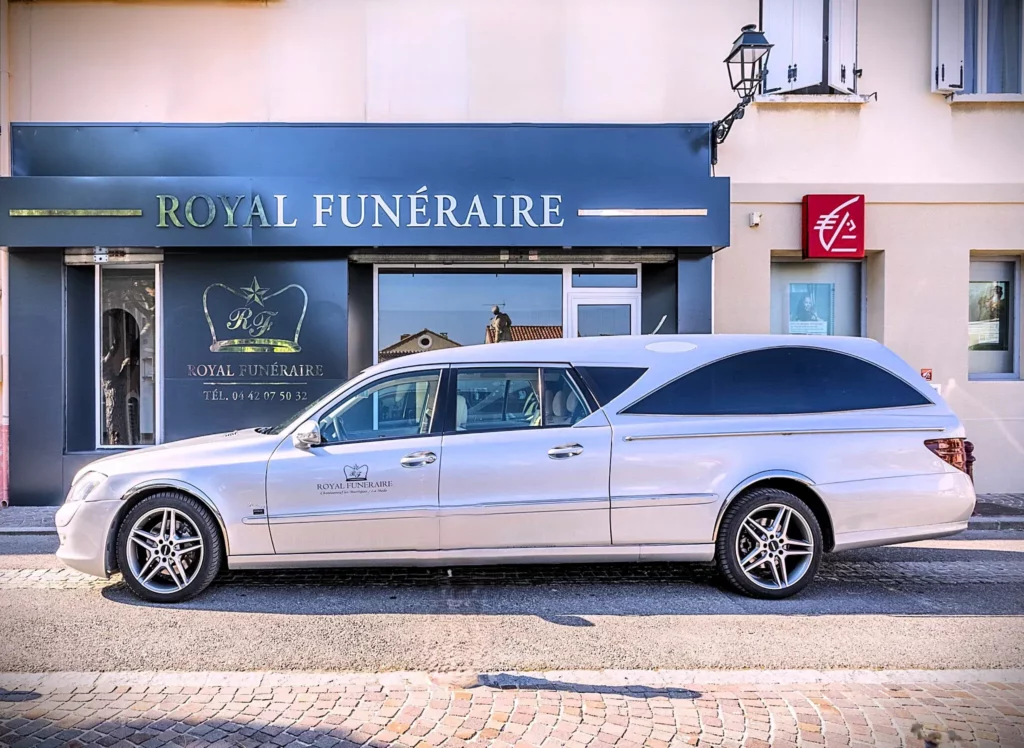 Corbillard gris stationné devant la façade de l'agence Royal Funéraire.