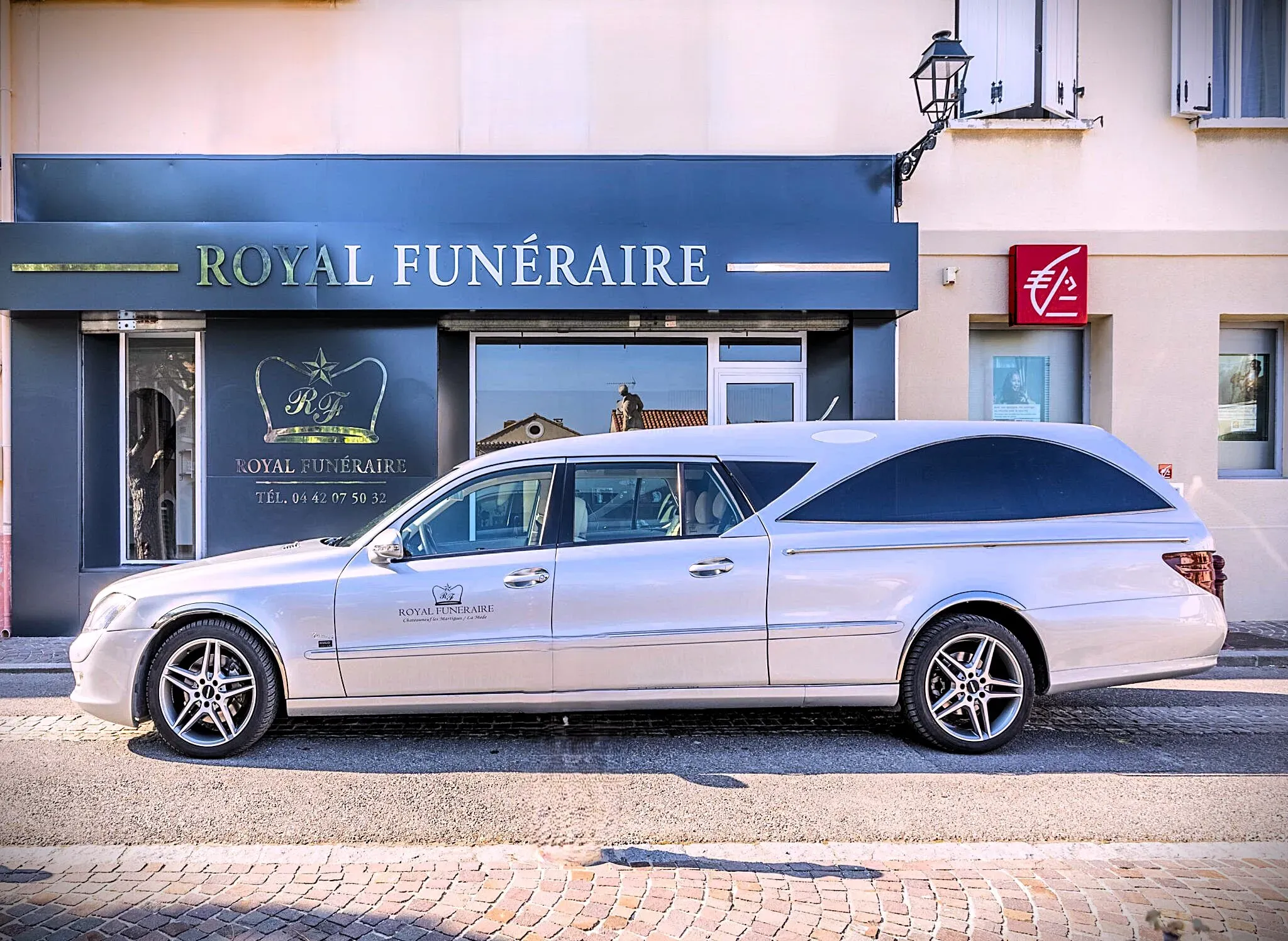 Corbillard gris stationné devant la façade de l'agence Royal Funéraire.