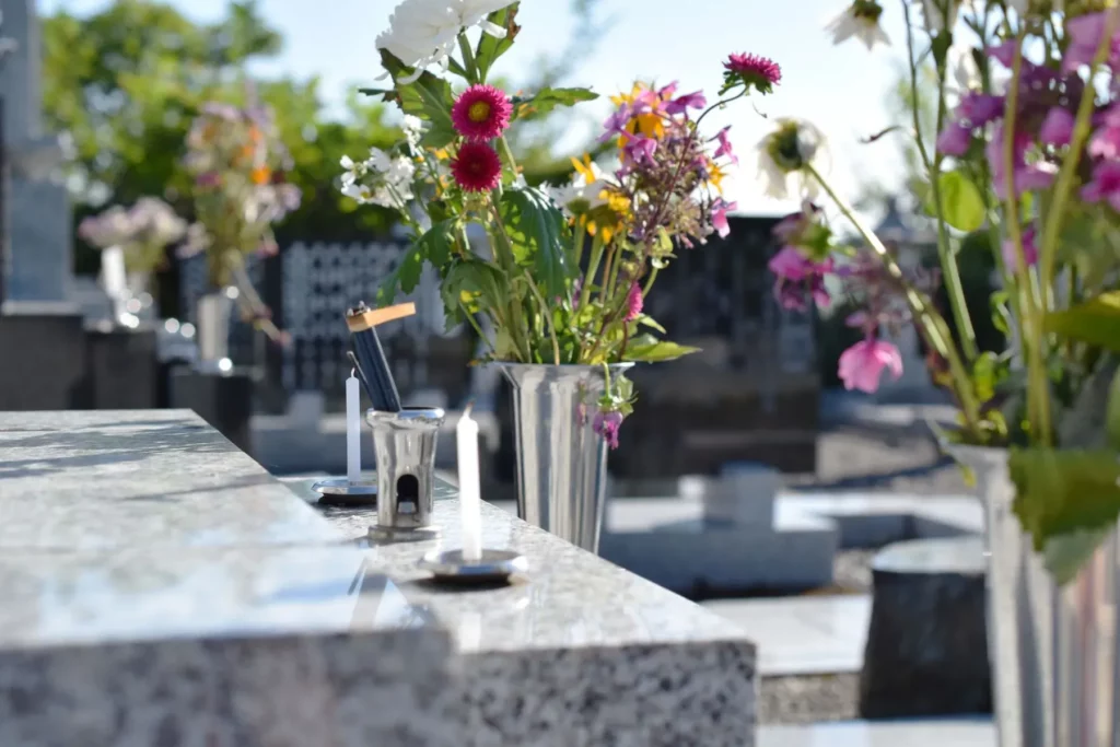Vases de fleurs et bougies allumées sur une pierre tombale en granite.